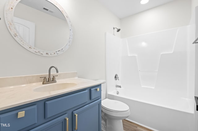 full bathroom featuring toilet, wood-type flooring, washtub / shower combination, and vanity