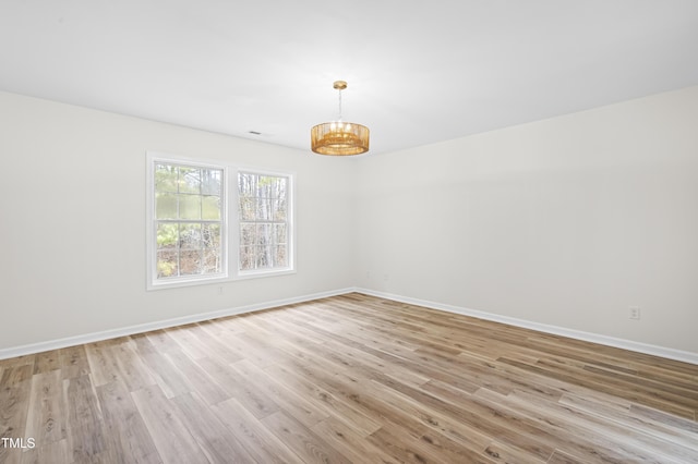 spare room featuring light hardwood / wood-style floors and a notable chandelier