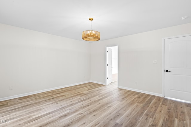 spare room with a chandelier and light hardwood / wood-style flooring