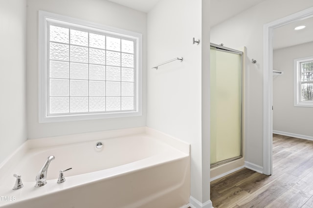 bathroom with hardwood / wood-style floors and shower with separate bathtub