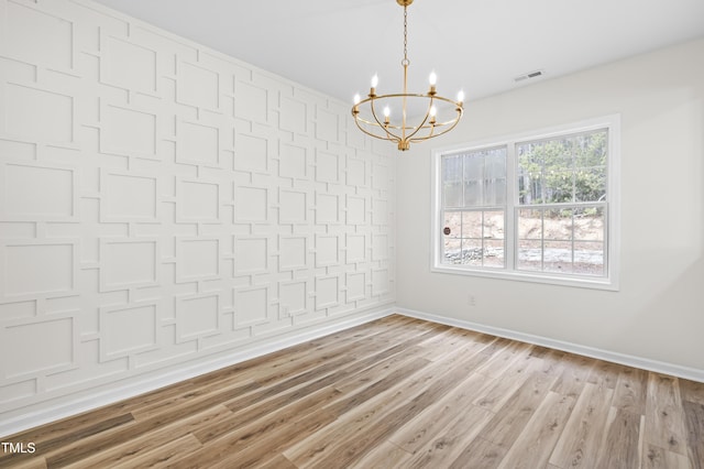 empty room with an inviting chandelier and light hardwood / wood-style flooring