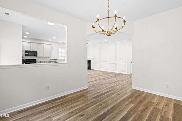 unfurnished dining area featuring sink, hardwood / wood-style floors, and a chandelier