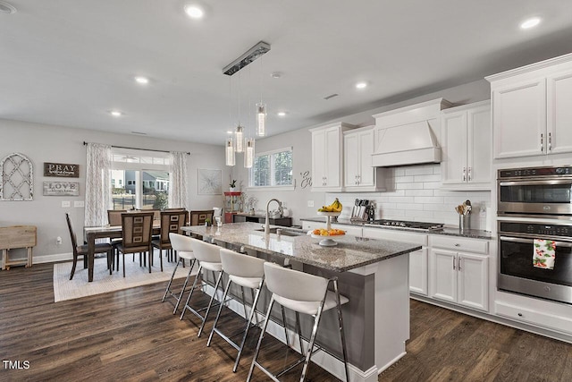 kitchen featuring sink, white cabinets, a kitchen island with sink, and appliances with stainless steel finishes