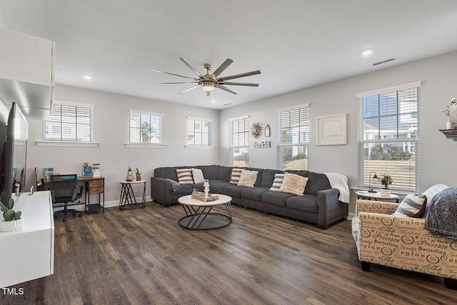 living room with dark wood-type flooring, ceiling fan, and a wealth of natural light