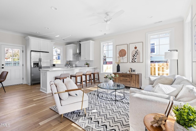 living room with ceiling fan, ornamental molding, and a wealth of natural light