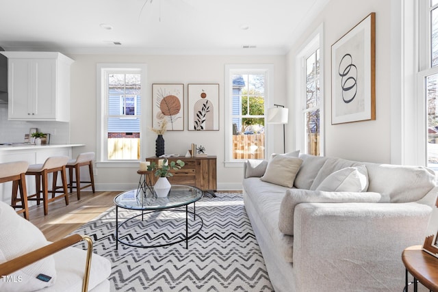 living room with light hardwood / wood-style floors, crown molding, and a wealth of natural light