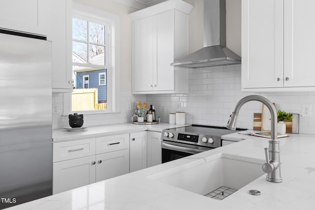 kitchen featuring stainless steel appliances, wall chimney exhaust hood, white cabinets, and decorative backsplash