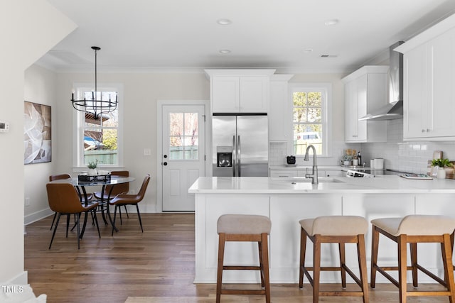 kitchen featuring an inviting chandelier, stainless steel fridge with ice dispenser, kitchen peninsula, white cabinets, and wall chimney range hood