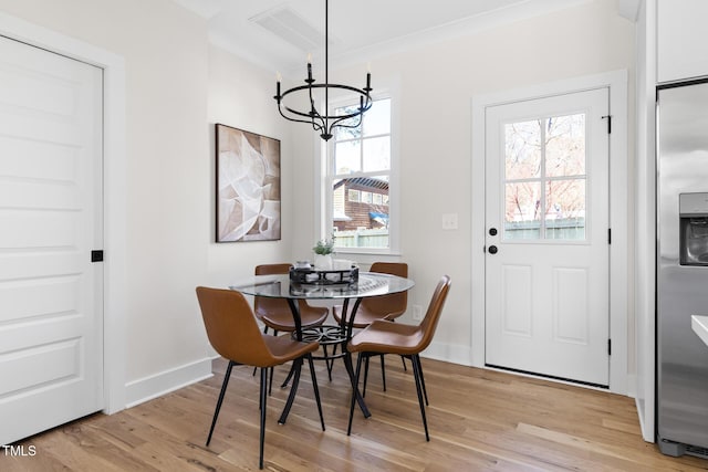 dining room featuring ornamental molding, a notable chandelier, and light hardwood / wood-style flooring