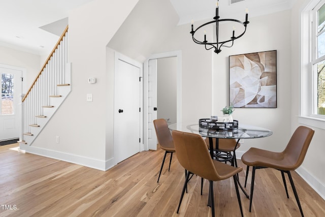 dining area with ornamental molding, light hardwood / wood-style floors, and a notable chandelier