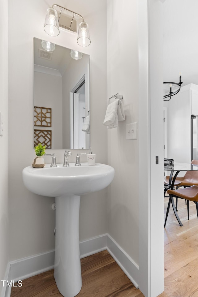 bathroom featuring sink, ornamental molding, and hardwood / wood-style flooring