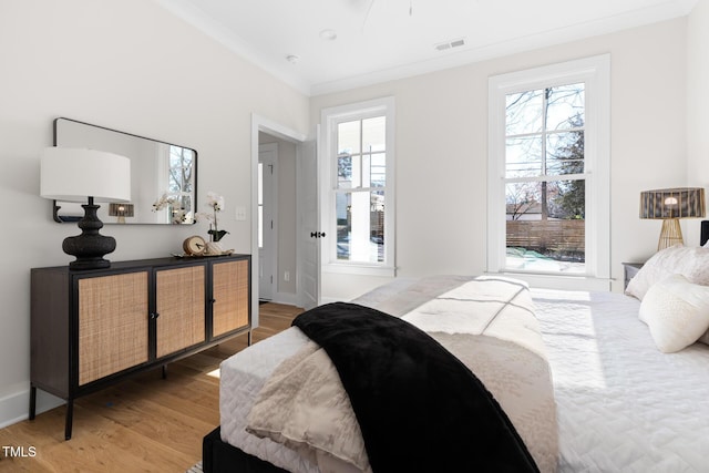 bedroom with ornamental molding, multiple windows, and wood-type flooring