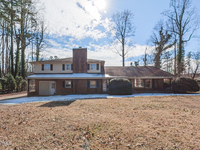 back of house with driveway, a chimney, and an attached garage