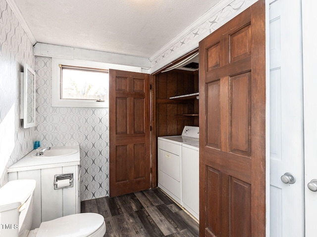 bathroom with toilet, wood-type flooring, sink, separate washer and dryer, and a textured ceiling