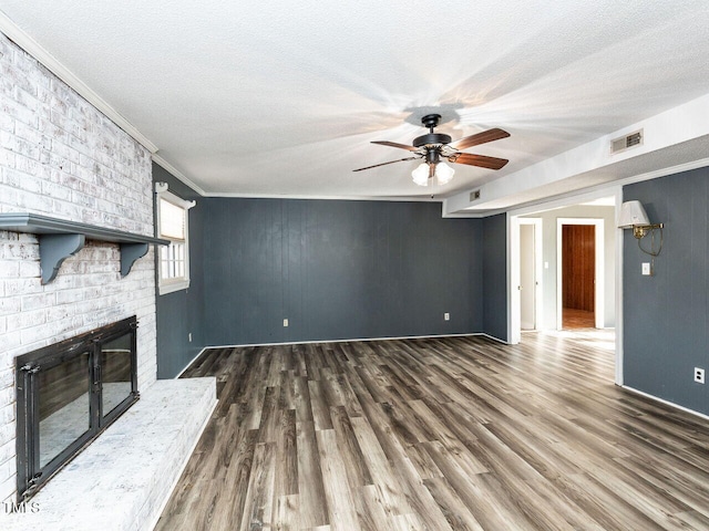 unfurnished living room featuring ceiling fan, a fireplace, crown molding, and a textured ceiling