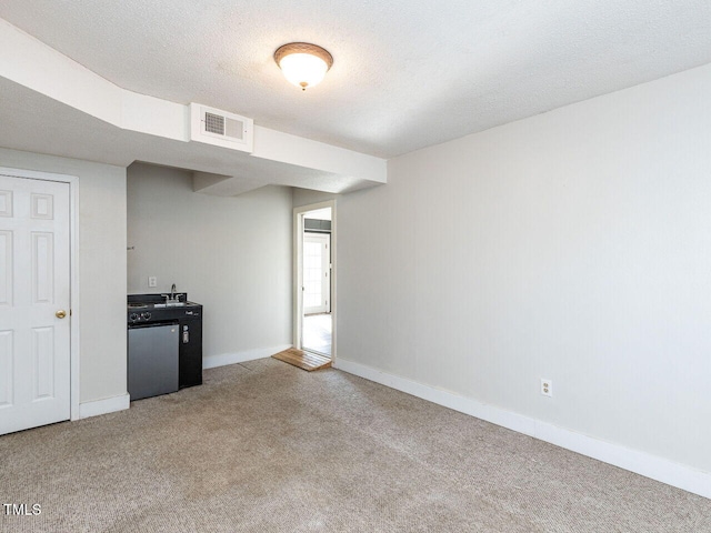 kitchen featuring carpet floors, fridge, and a textured ceiling