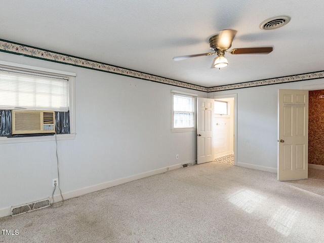 empty room featuring cooling unit, ceiling fan, light colored carpet, and plenty of natural light