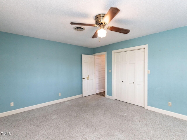 unfurnished bedroom featuring ceiling fan, a closet, a textured ceiling, and carpet flooring