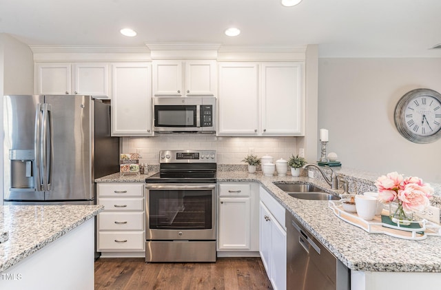 kitchen with sink, appliances with stainless steel finishes, white cabinetry, dark hardwood / wood-style floors, and light stone countertops