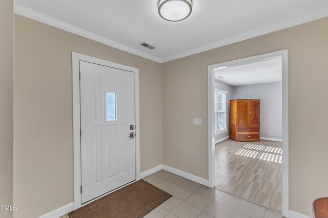 foyer entrance featuring light tile patterned floors and crown molding