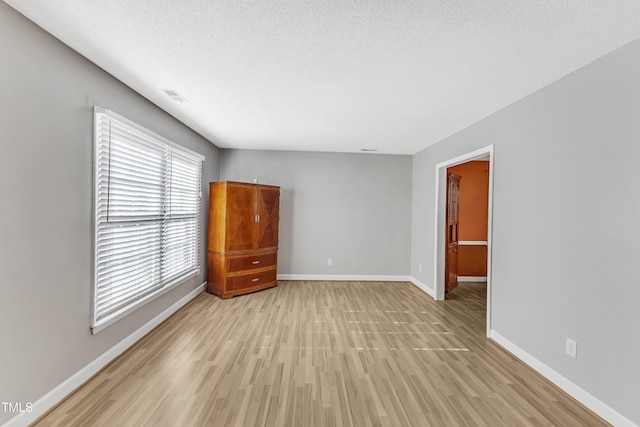 unfurnished room featuring a textured ceiling and light hardwood / wood-style flooring