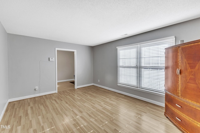 interior space with a closet, a textured ceiling, multiple windows, and light hardwood / wood-style flooring