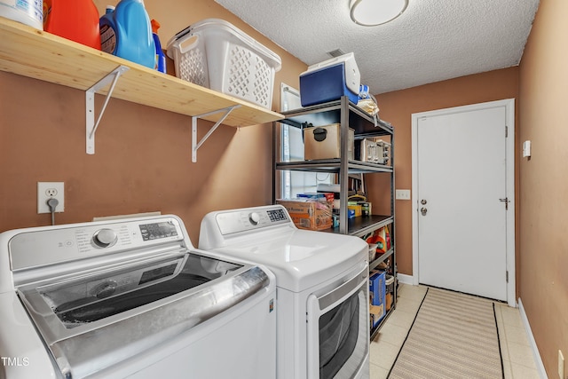 clothes washing area with light tile patterned floors, washing machine and clothes dryer, and a textured ceiling