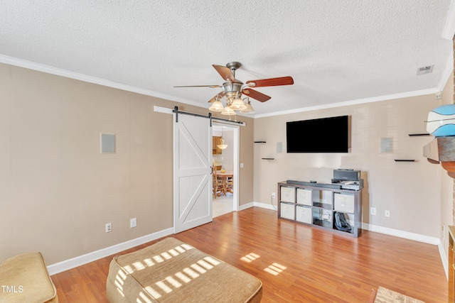 living room with ceiling fan, crown molding, a barn door, and hardwood / wood-style flooring