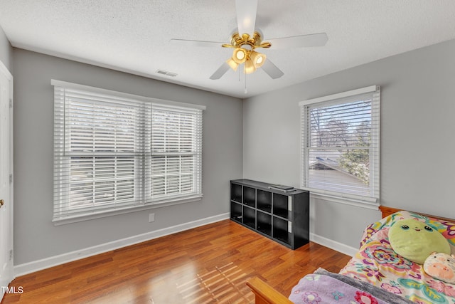 sitting room featuring ceiling fan, plenty of natural light, a textured ceiling, and hardwood / wood-style flooring