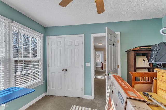 carpeted bedroom with a textured ceiling, ceiling fan, and a closet