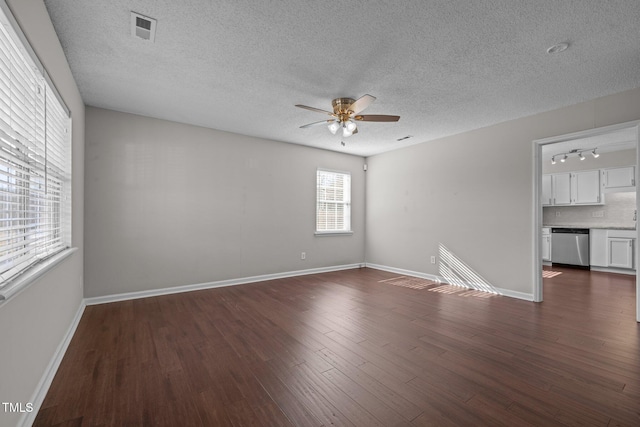 spare room with rail lighting, dark hardwood / wood-style floors, a textured ceiling, and ceiling fan