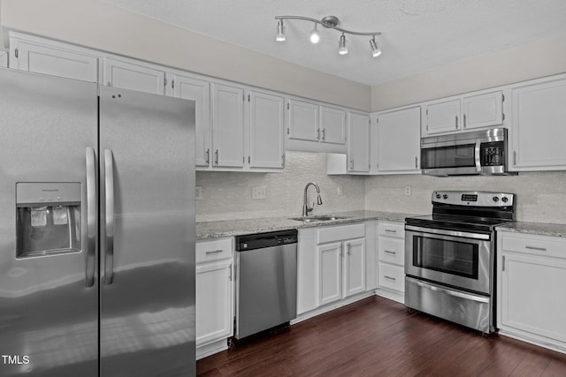 kitchen featuring appliances with stainless steel finishes, light stone countertops, sink, and white cabinets