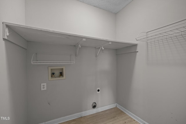 laundry room with electric dryer hookup, washer hookup, a textured ceiling, and light hardwood / wood-style flooring