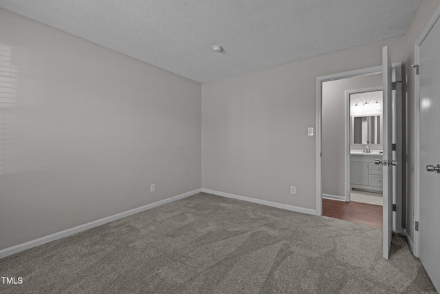 carpeted empty room featuring sink and a textured ceiling