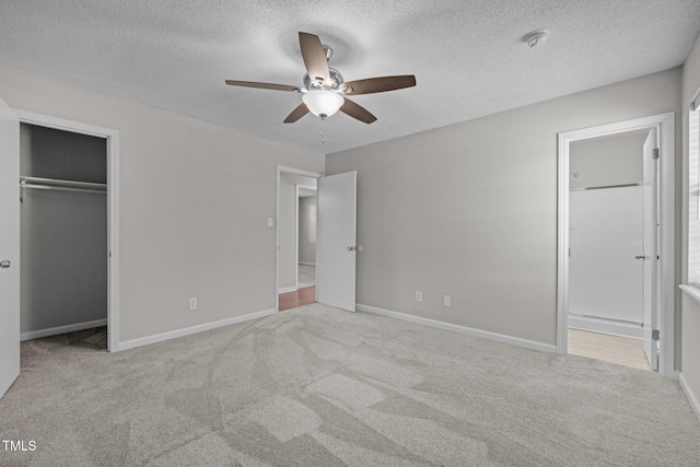 unfurnished bedroom with a textured ceiling, light colored carpet, a closet, and ceiling fan