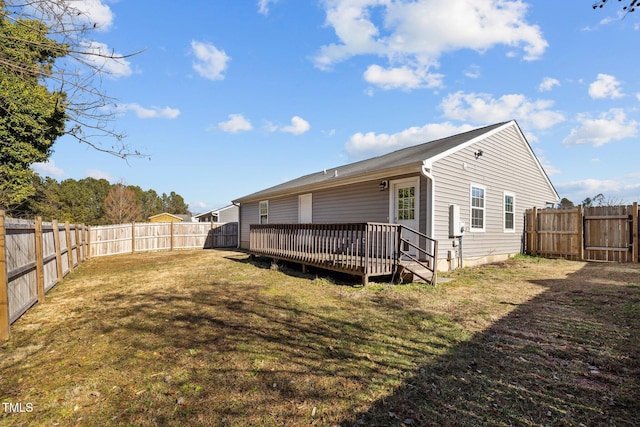 rear view of house with a wooden deck and a yard