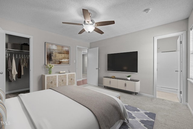 carpeted bedroom featuring a walk in closet, connected bathroom, ceiling fan, and a closet