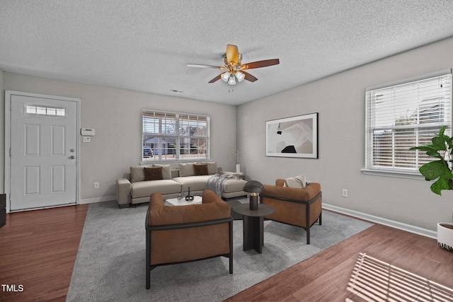 living room with ceiling fan, dark hardwood / wood-style floors, and a textured ceiling