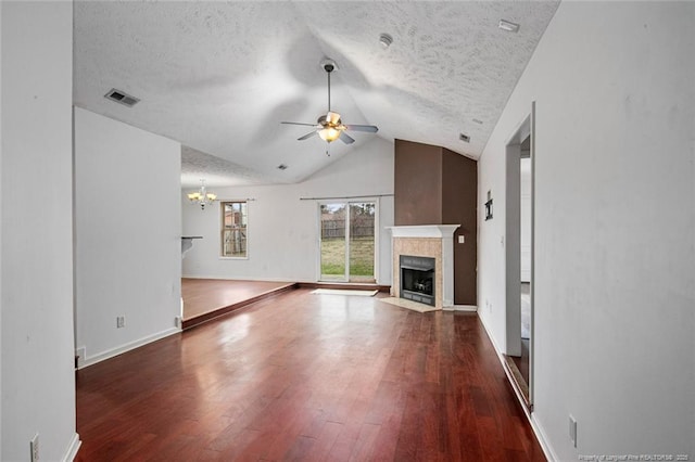 unfurnished living room with a textured ceiling, dark wood-type flooring, vaulted ceiling, and ceiling fan with notable chandelier