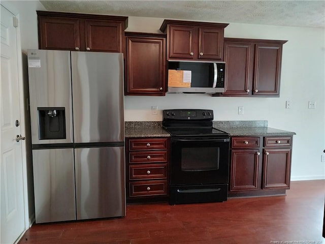 kitchen featuring dark hardwood / wood-style floors, dark stone countertops, stainless steel appliances, and a textured ceiling