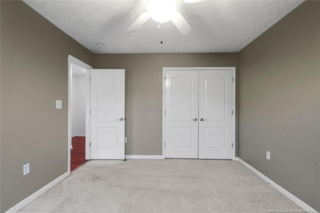 unfurnished bedroom with a textured ceiling, ceiling fan, a closet, and light colored carpet