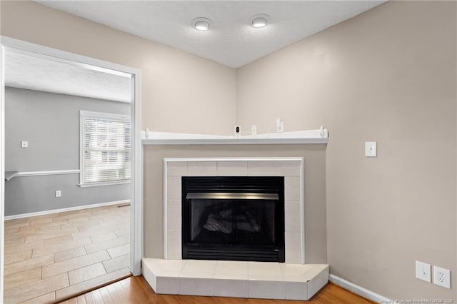 details featuring a tile fireplace, a textured ceiling, and hardwood / wood-style floors