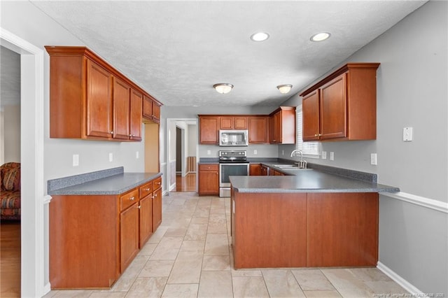 kitchen with sink, light tile patterned flooring, kitchen peninsula, and appliances with stainless steel finishes