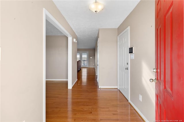 corridor with a textured ceiling, french doors, and hardwood / wood-style flooring