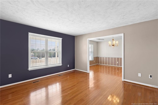 unfurnished room with a chandelier, hardwood / wood-style floors, and a textured ceiling