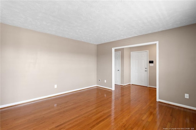 empty room featuring a textured ceiling and hardwood / wood-style flooring