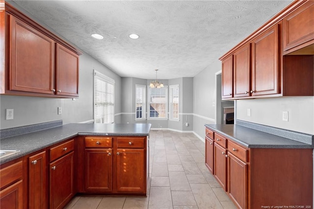 kitchen with decorative light fixtures, a textured ceiling, light tile patterned floors, kitchen peninsula, and a chandelier