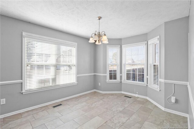 unfurnished room featuring an inviting chandelier, a textured ceiling, and light tile patterned floors