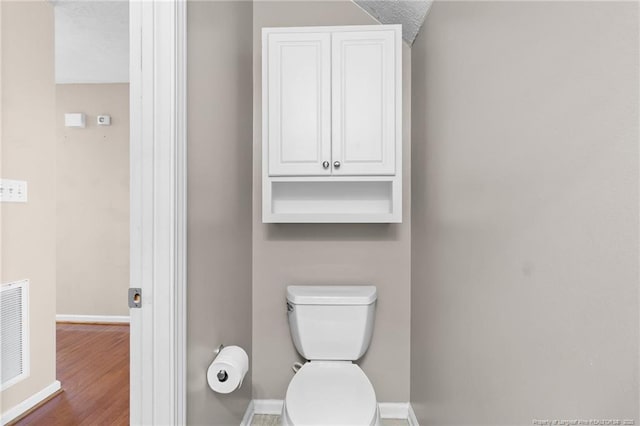 bathroom featuring toilet, a textured ceiling, and hardwood / wood-style floors