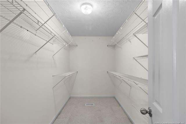 walk in closet featuring light colored carpet